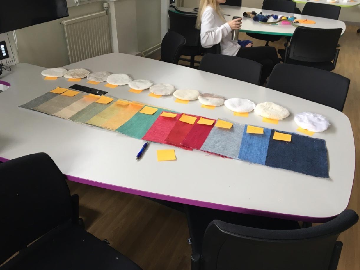 Photo of table with many fabric swatches of different colours and textures on it