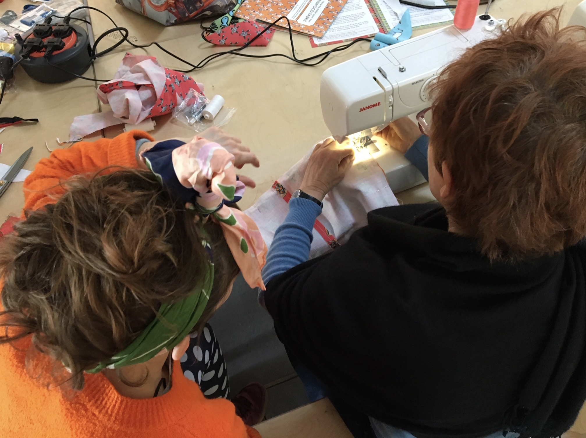 Two people sewing with a sewing machine